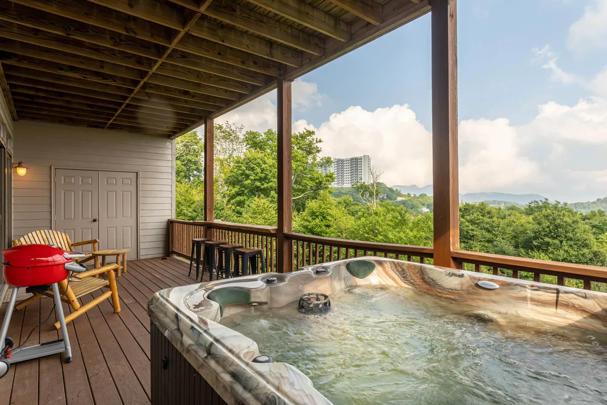 A welcoming view of the deck featuring a hot tub, seating area, and grill, all set against a stunning mountain backdrop. The arrangement is inviting, designed for relaxation, entertaining, or simply enjoying the natural beauty from sunrise to sunset.