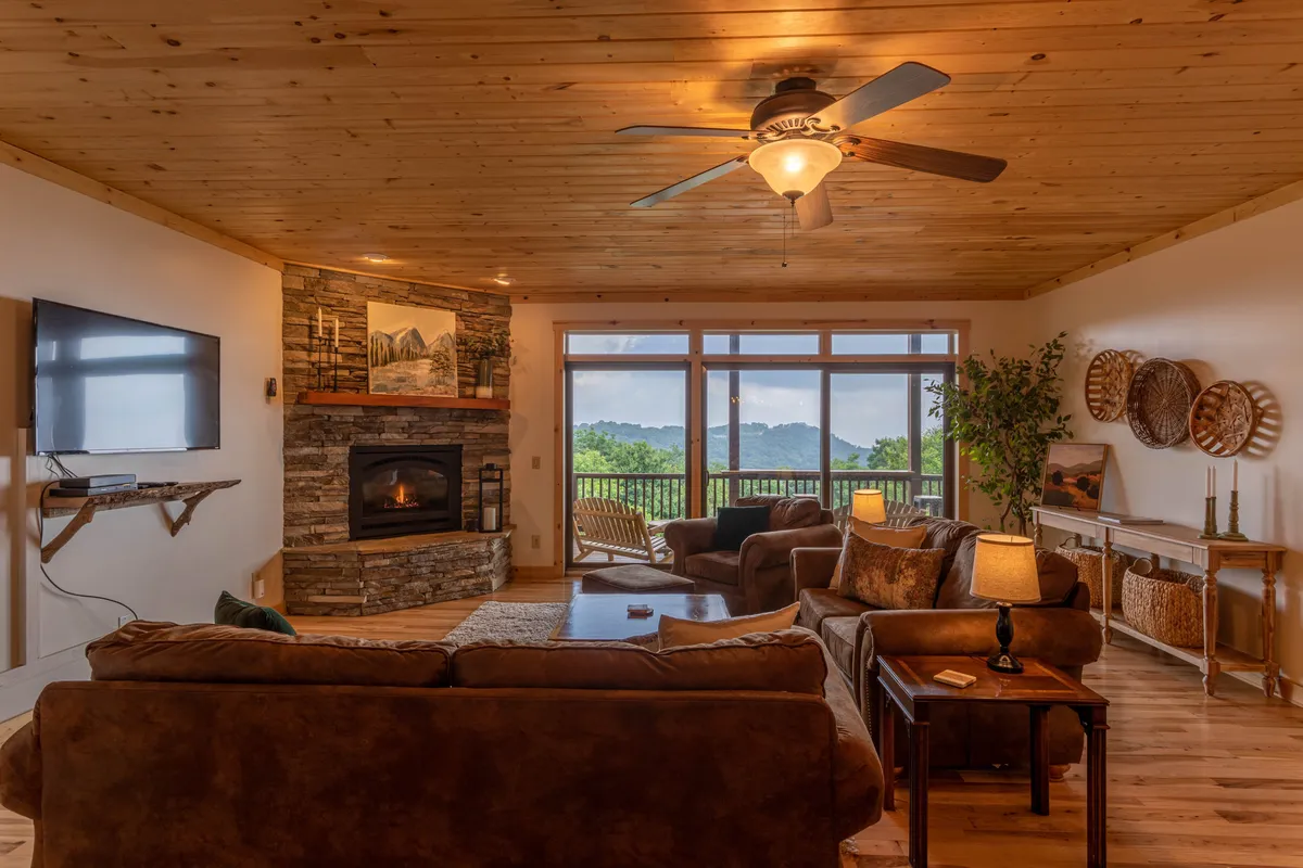 A warm, inviting living room with a fireplace, comfortable seating, and large windows revealing a snowy landscape outside. The space is cozy, perfect for relaxing after skiing.
